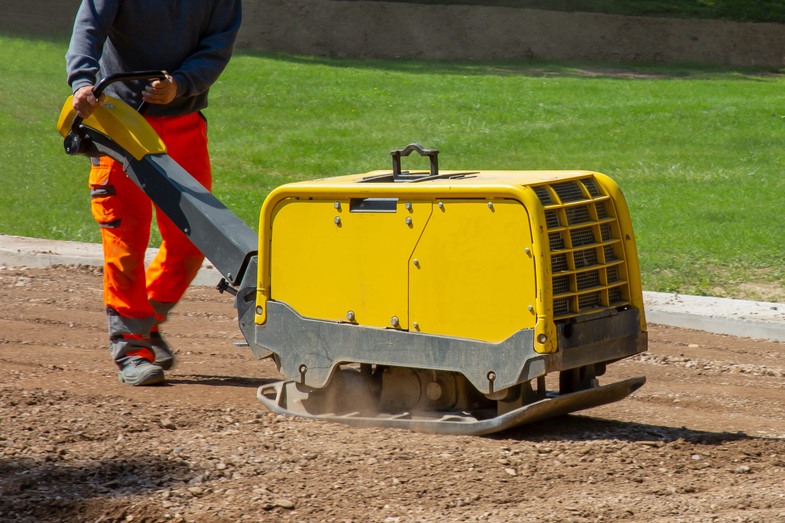 A construction worker working on the road with a vibratory plate