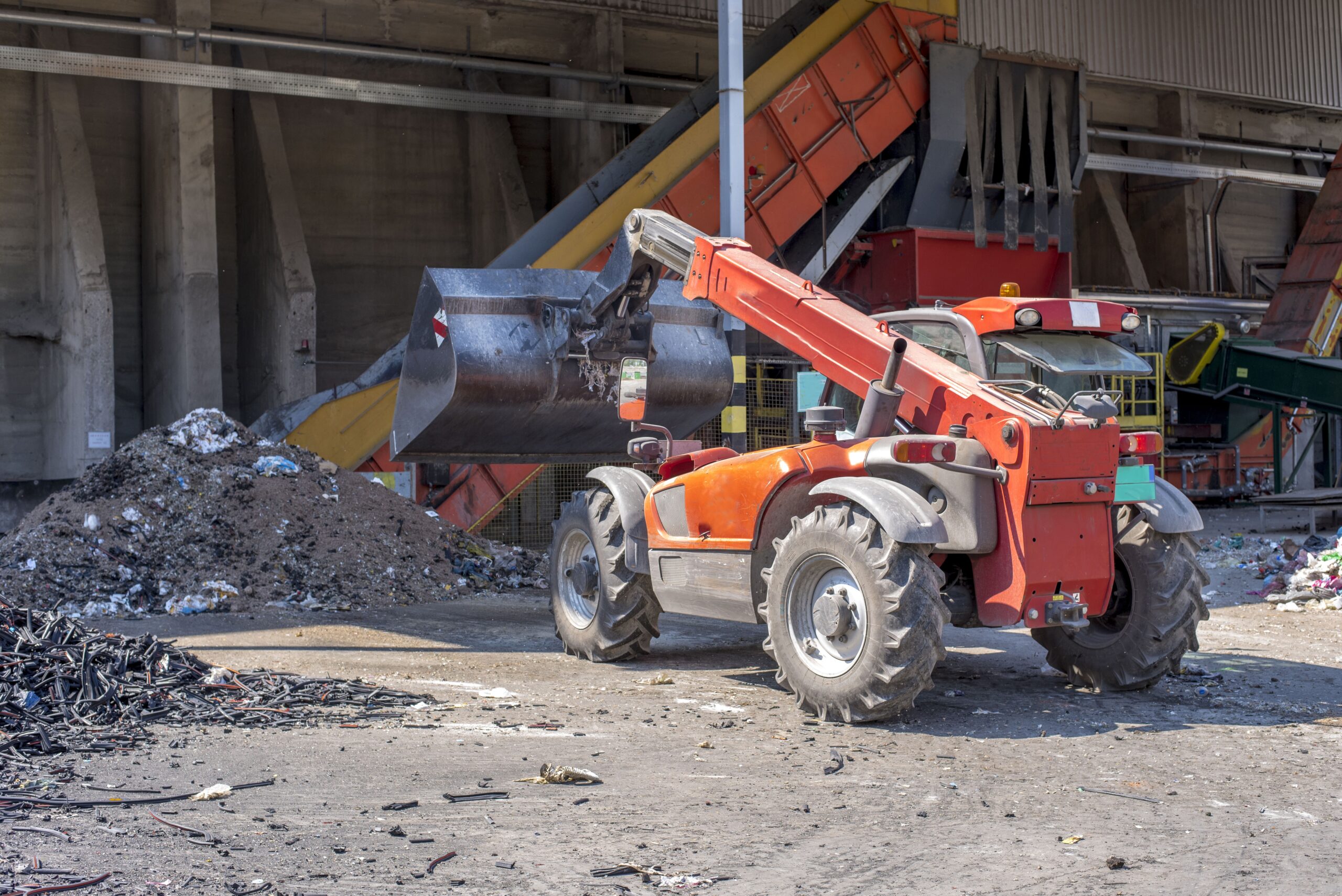 A loader transporting soil and waste materials at a waste treatment plant